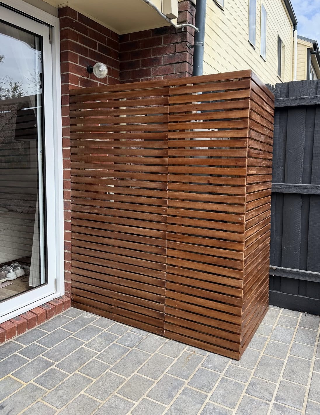 Timber slat enclosure around a hot water service